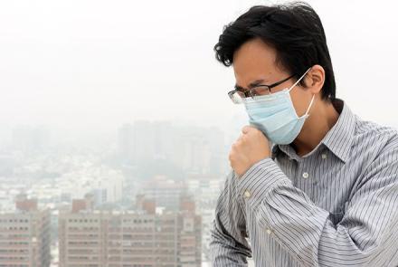 Image of a man with a mask in a polluted city. 