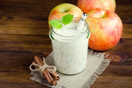 White apple and cucumber smoothie in a glass with apples 