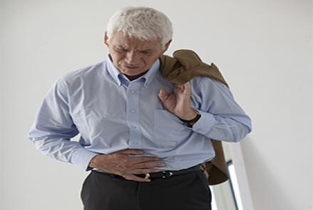 A person in a shirt and trouser holding his jacket with one hand and his stomach with another