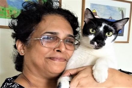 Image: Vidya, with spectacles and black hair holding a black and white on her left shoulder