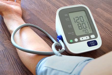 A person's arm cuffed by a BP monitor