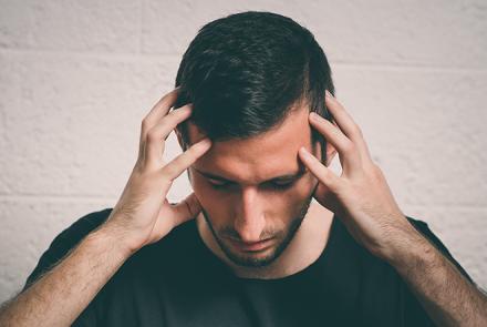 a man holding his head due to throbbing migraine headache