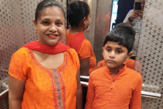 Barnana with her son who is on the autism spectrum. Both are in orange and behind them are blurry reflections in the mirror