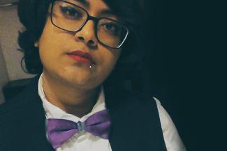 A spectacled woman with a white shirt, purple bow tie and black waist coat