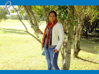 Shilpi standing in a park with the support of a cane