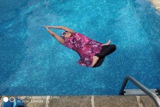 A woman in a pink swim suit doing yoga in a pool