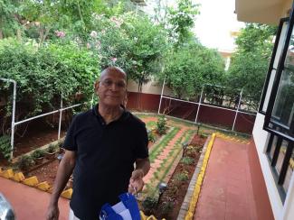 Mr Balagopal in a black t-shirt in front of the garden he loves to work in
