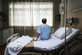 A man sitting in hospital gown on a hospital bed