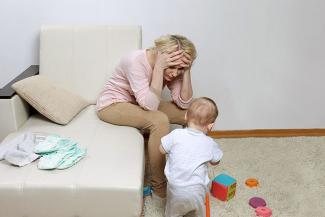 Pic shows a frazzled and hassled new mom with post partum depression with a young kid