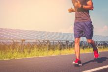 Image: A stock pic of a man running on a road in purple shirts, greyish-purplish t-shirt, red shoes