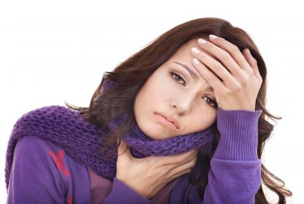 Woman in purple sweater and muffler holding her head and neck in distress