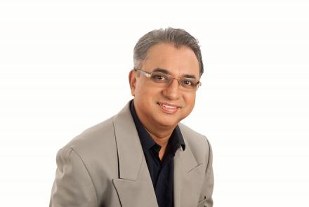 Image: Vijay Nallawala in a black shirt and grey jacket looking at the camera