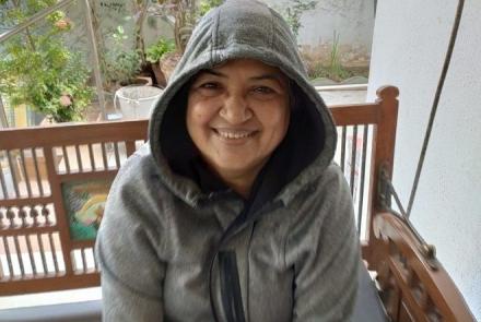 A woman a bladder cancer survivor in a grey hoodie sitting on a wooden swing 