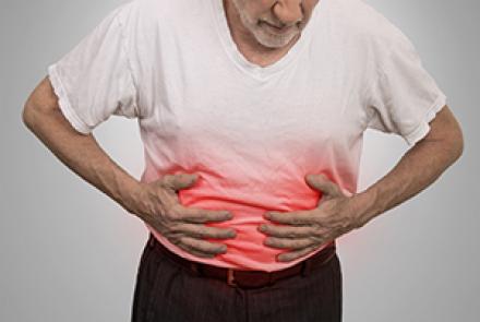 Stock image of a person in a white shirt feeling discomfort in stomach 