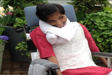 Bhavna is person with cerebral palsy in a red and white dress on a wheelchair