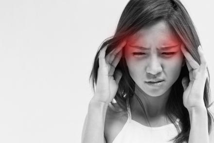 Stock image of a woman in black and white with a red aura on her temples depicting migraine
