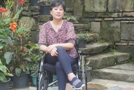 Nagaland Disability Activist and commissioner on a wheelchar in front of a building and some plants