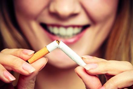 Stock pic of the bottom half of a woman's face smiling and breaking a cigarette as she tells her experience of how she quit smoking 