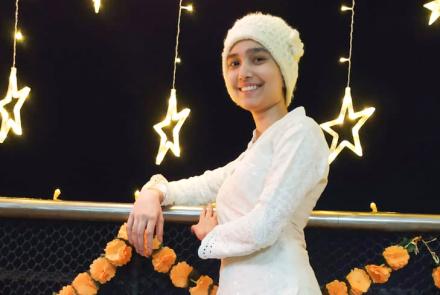 A teenager, a lymphoblastic leukemia survivor in a white dress and headcover 
