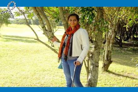Shilpi standing in a park with the support of a cane