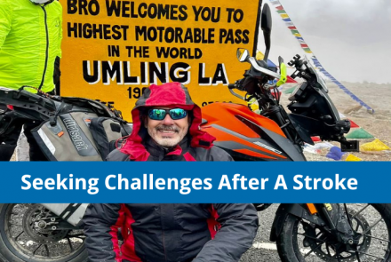 Picture of a stroke survivor on umling la pass in front of his bike and the text on a blue strip Seeking Challenges After a Stroke 