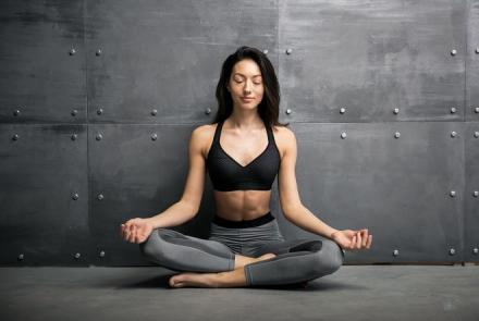 Image: Woman with black hair, in yoga leotards sitting in padmasana (lotus pose)
