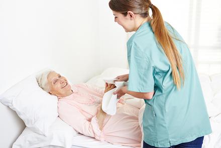 A nurse assisting a female bed ridden patient 