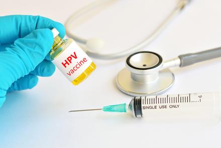image of a stethoscope and a gloved hand holding a bottle marked hpv vaccine