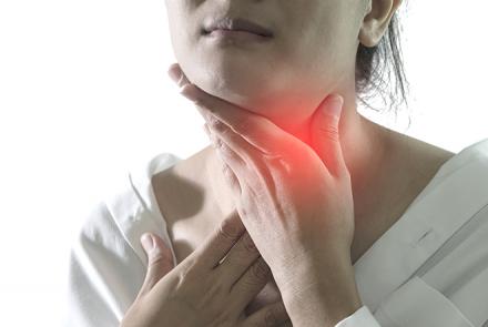 partial image of a woman holding her neck indicating a thyroid problem