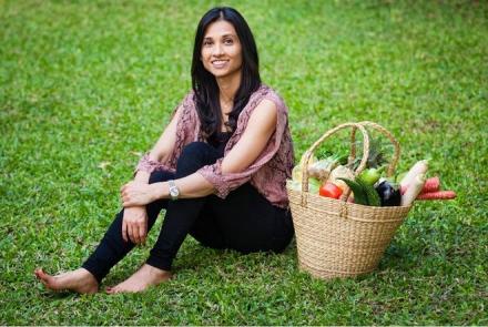 Priya sitting on a green patch with a basket of fresh food next to her sharing her management of hypothyroidism