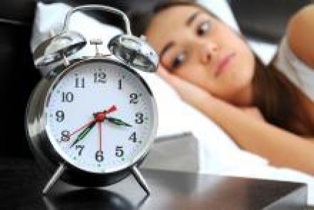 A woman lying awake looking towards a clock 