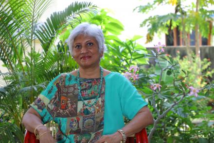 Usha in front of a palm tree in her garden